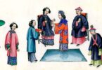 Pernikahan Dinasti Qing. Orang tua mempelai pria duduk. Pengantin wanita adalah yang di tengah mengenakan gaun merah dan topi baja biru, mempersembahkan teh untuk ibu mertuanya. Pengantin pria biasanya memakai selempang berbentuk "X" di dadanya. (Kredit: Wikimedia Commons)